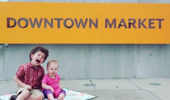 Downtown Market Kids SItting in Front of Yellow Sign