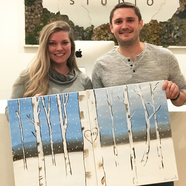 Brush Studio couple holding paintings