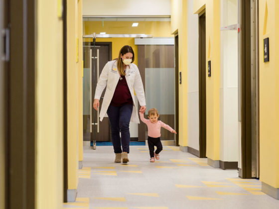 U M Health West pediatrician walking toddler down hallway