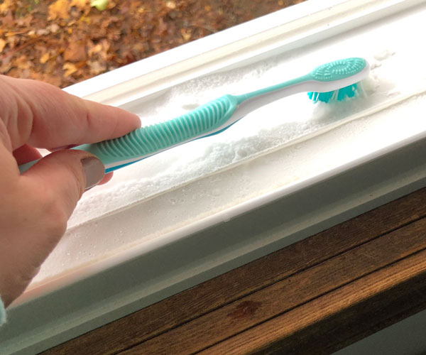 using toothbrush to clean window track