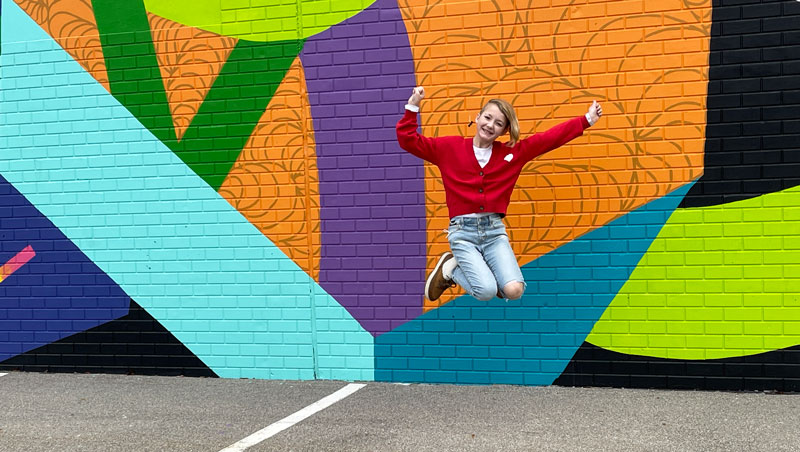 Girl jumping in front of Murals near downtown market Grand Rapids.