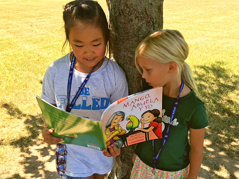Legacy Christian immersion students reading under tree