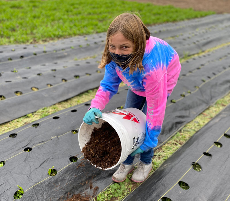 Rockford Christian School girl pouring soil in garden
