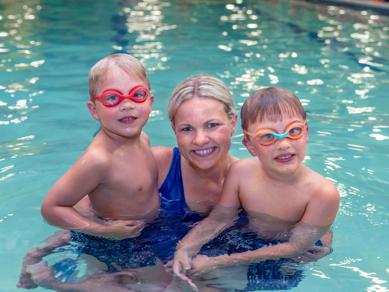 Goldfish swim school kids in pool with instructor