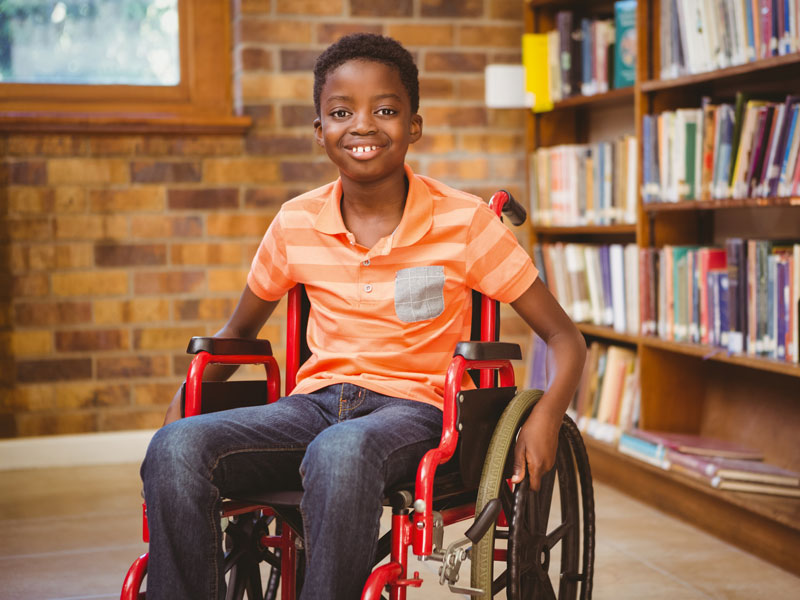 boy in wheelchair in library happy
