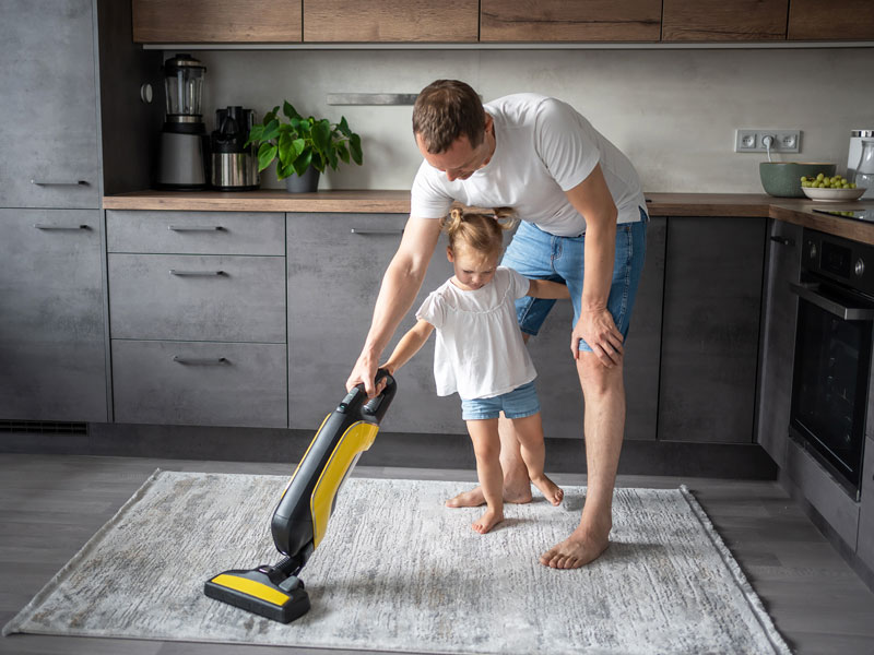 Dad cleaning house with daughter vacuum