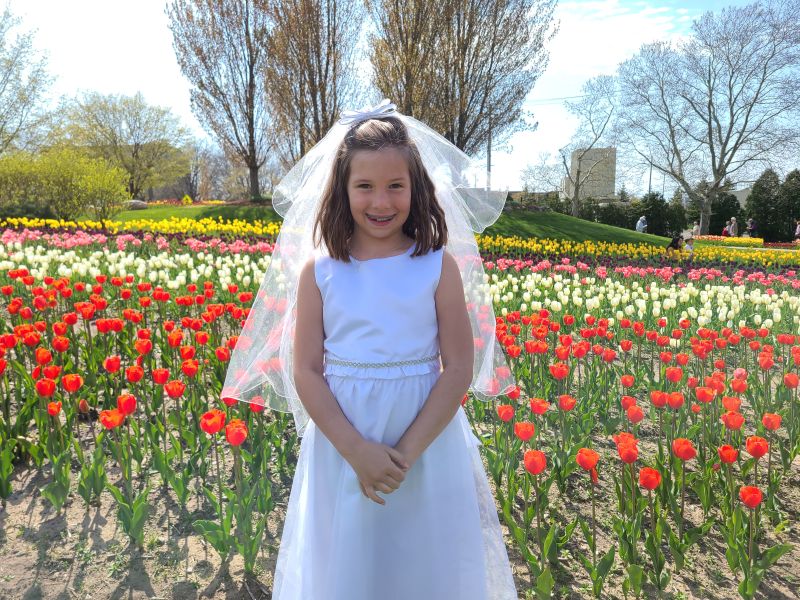 Window on the Waterfront girl in first communion dress by tulips