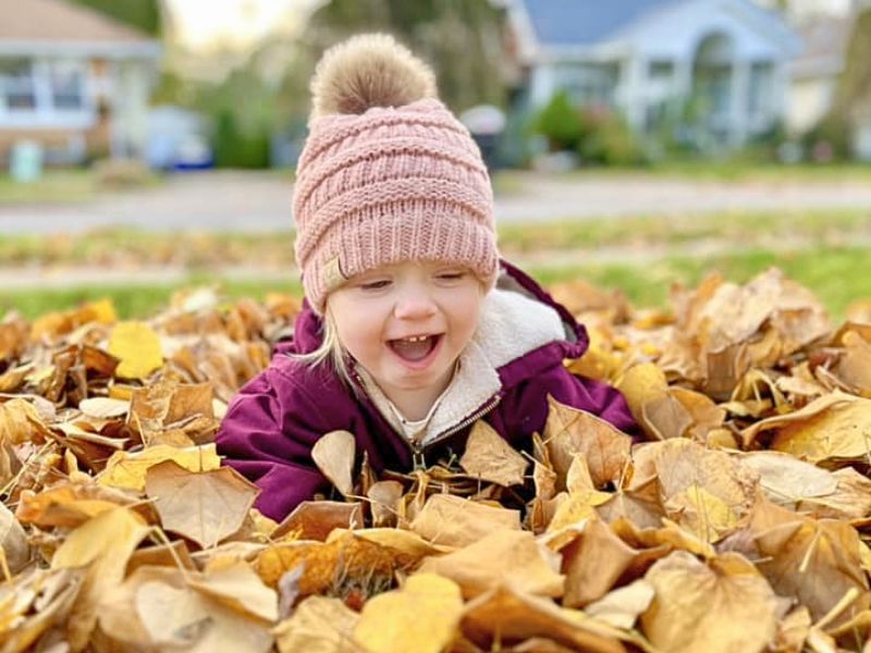 fall activities toddler in pile of leaves