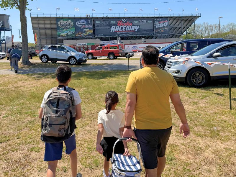 Family walking from the parking lot to the entrance of Berlin Raceway.