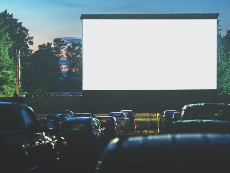 drive in movie theater cars in front of screen at dusk canva