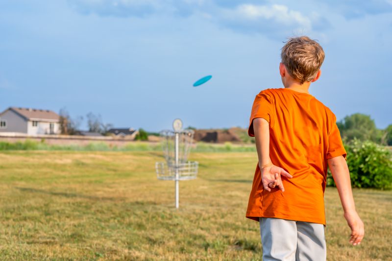 young boy playing disc golf
