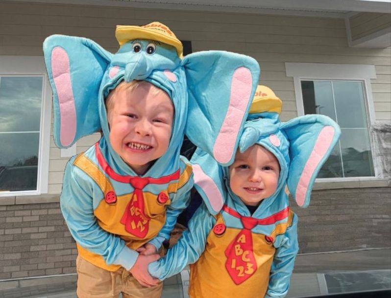 Learning Experience alpine two kids in elephant costumes outside building wide