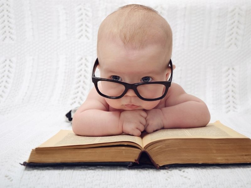 eye doctor : baby wearing glasses while resting on book canva