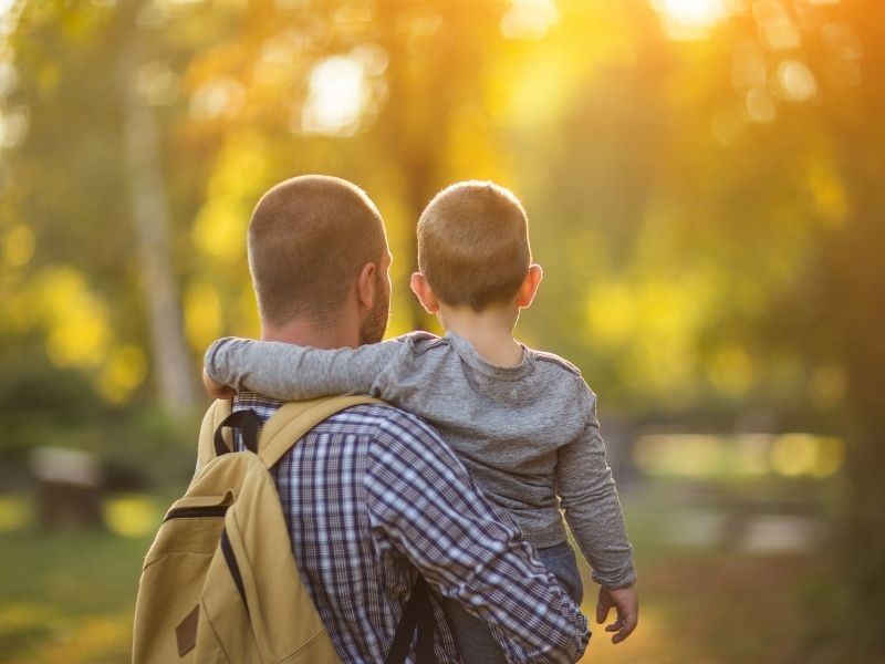 foster parent dad holding boy outside 